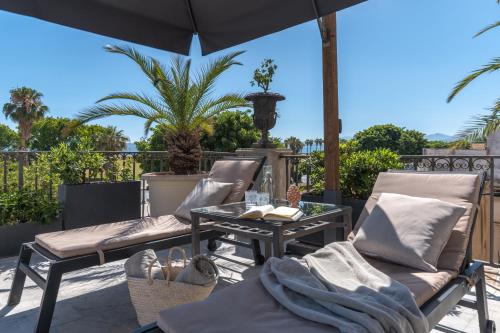 a patio with two chairs and a table and an umbrella at L' Hôtellerie Easy Suites in Palermo
