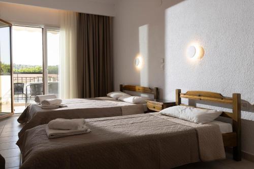a hotel room with two beds and a balcony at Μυρτιές-Mirties in Siviri