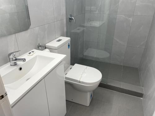 Un baño blanco con inodoro y lavabo. en County Lodge Motor Inn, en West Wyalong