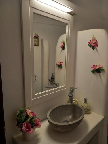 a bathroom with a sink with a mirror and flowers at Το Πέτρινο in Kithnos
