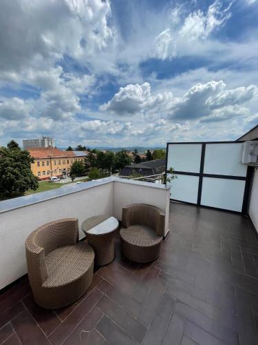 a balcony with two chairs and a table and chairs at Garni Hotel Ema in Kragujevac