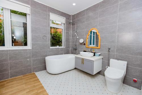 a bathroom with a tub and a toilet and a sink at Nhà phố ven Biển view hồ cho 6-8 pax in Bình Tú