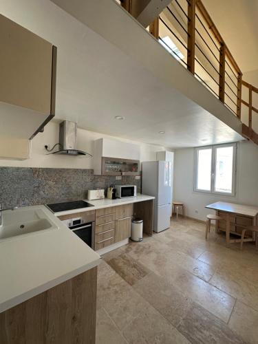 - une cuisine avec des appareils électroménagers blancs et une table dans l'établissement Appartement avec vue sur l église des Saintes, à Saintes-Maries-de-la-Mer