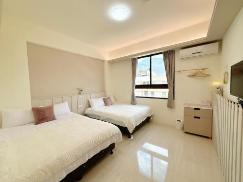 een hotelkamer met twee bedden en een televisie bij 春日SpringDay花蓮包棟民宿 in Hualien