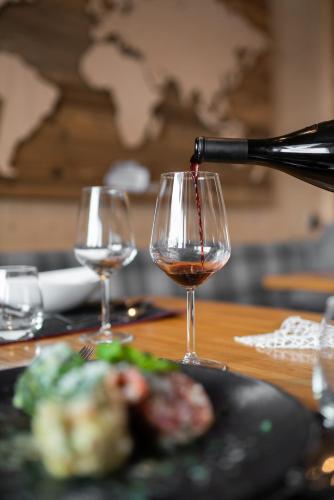 a bottle of wine being poured into a wine glass at Hotel Das Lisann in Pfelders