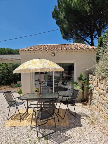 un patio avec une table, des chaises et un parasol dans l'établissement Tres bel hébergement ensoleillé les Romarins, à Le Val