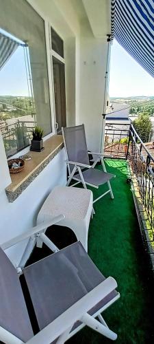 two chairs and a table on a balcony with green grass at Къща за гости Веселина - Ивайловград in Ivaylovgrad