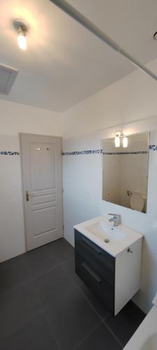 une salle de bain blanche avec un lavabo et un miroir dans l'établissement Maison de vacances, à Saint-Clément-de-Rivière