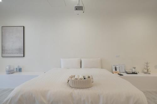 a white bedroom with a white bed with a basket on it at Bianca in Tainan