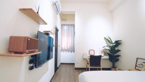 a room with a bed and a desk and a television at 咻咻宿 Xiuxiu 電梯宅 in Taitung City