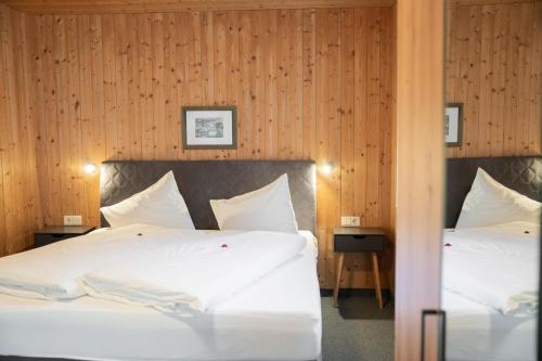 two beds in a room with wood paneling at Hotel Das Lisann in Pfelders