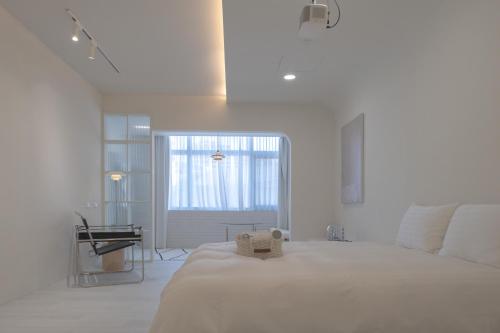 a white bedroom with a large bed and a window at Bianca in Tainan