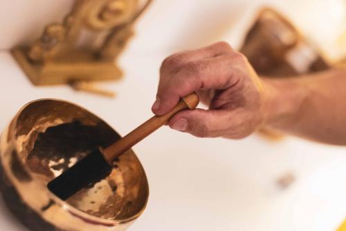 a hand holding a wooden spoon in a frying pan at Paddock Lodge - Suites Wellness & Chambres d'hôtes in Stoumont
