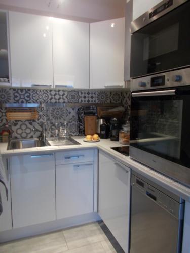 une cuisine avec des armoires blanches et des appareils en acier inoxydable dans l'établissement appartement nice proche mer, à Nice
