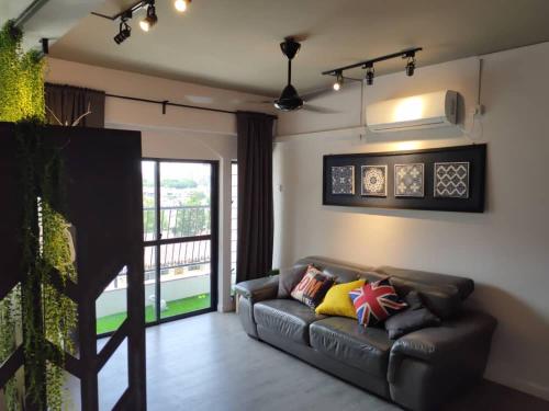 a living room with a leather couch and a balcony at Cozy Loft oversee Penang Hill in Ayer Itam