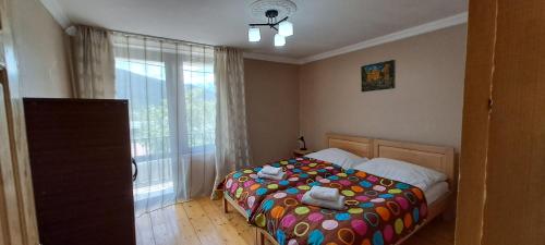 a bedroom with a bed with a colorful comforter and a window at Guesthouse Robi in Mestia
