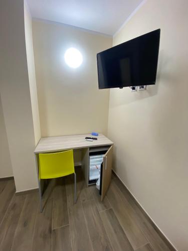 a desk with a yellow chair and a tv on a wall at Sogni d'insonnia in San Sosti