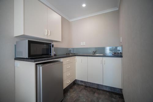a kitchen with white cabinets and a microwave at Parklands Motel & Apartments Te Anau in Te Anau