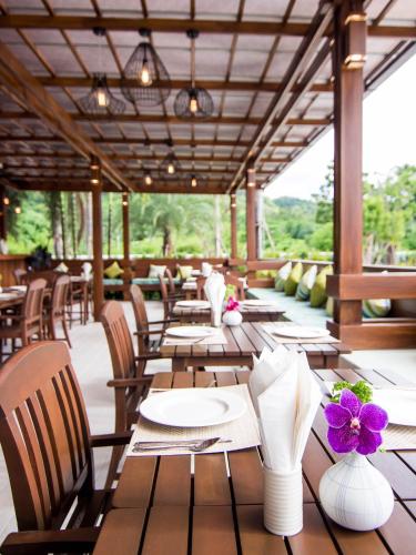 a restaurant with wooden tables and chairs and purple flowers at The Phu Beach Hotel - SHA Plus in Ao Nang Beach