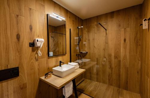 a bathroom with wooden walls and a sink and a shower at Hotel Kranjska Gora in Kranjska Gora