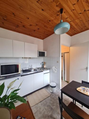 une cuisine avec des armoires blanches et un plafond en bois dans l'établissement La Gleyzinière 2, à Allevard