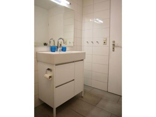 ein weißes Badezimmer mit Waschbecken und Dusche in der Unterkunft Unterdeck in Wittdün