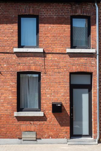 a brick building with three windows and a door at ViaAmbioriX in Tongeren