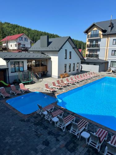a swimming pool with lounge chairs and a hotel at Guest House Zatyshnyi Dvir in Bukovel