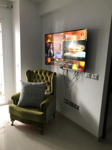 a living room with a couch and a tv on a wall at Residence amwej sousse in Sousse