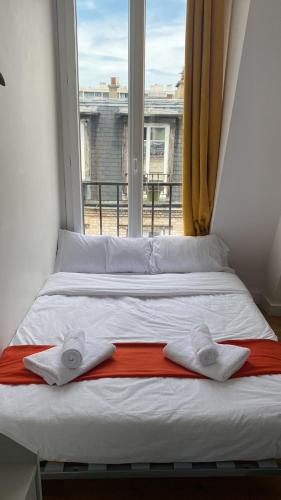 - un lit avec 2 serviettes dans une chambre avec fenêtre dans l'établissement Charmante petite chambre vue sur les toits de Paris avec ascenseur - quartier animé et proche des jeux olympiques, à Paris