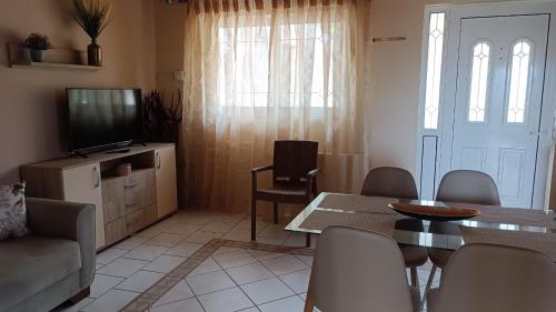 a living room with a television and a table and chairs at Spiti TRIVIZAS in Agrós