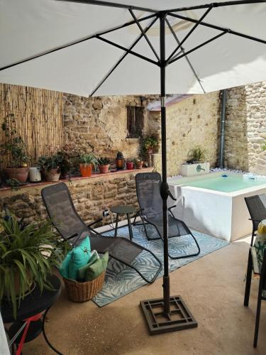 - un parasol sur une terrasse avec des chaises et une table dans l'établissement Maison de village à deux pas de la rivière, à Remoulins