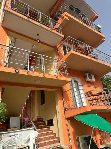 an orange building with stairs and an umbrella at Themis Apartment in Kotor