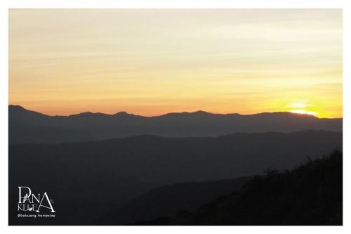 a sunset over a mountain range with the sun in the sky at Panakluea at Kokuang Homestay in Ban Na Lae