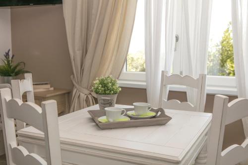 a white dining room table with two cups and chairs at Appartamento il Punto in Perugia
