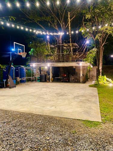 an outdoor basketball court at night with lights at บ้านต้นไม้โฮมสเตย์อุทัยธานี in Uthai Thani