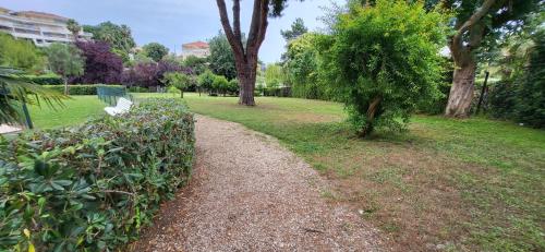 un chemin dans un parc avec un banc et des arbres dans l'établissement Spacieux 2 pièces vue mer piscine, à Antibes