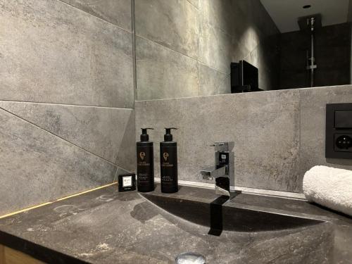 - une salle de bains avec 2 bouteilles sur un lavabo dans l'établissement La Pepite Des Aiguilles - Calme - Cosy, aux Houches