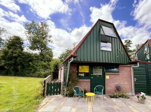 a house with a green roof and a table and chairs at Happy Little Maya Bee in Nieuwe-Niedorp