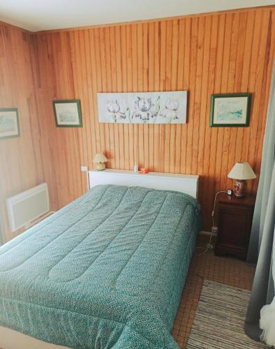 une chambre avec un lit et des murs en panneaux de bois dans l'établissement Le Lotus, à Saint-Jean-de-Monts