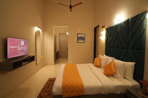 a bedroom with a large bed and a tv at Gaurav Lords Resort in Srīvardhan