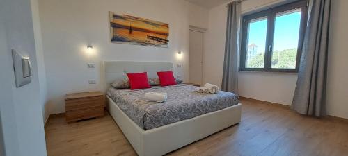 a bedroom with a bed with red pillows and a window at Mozart Haus camere in Quartu SantʼElena