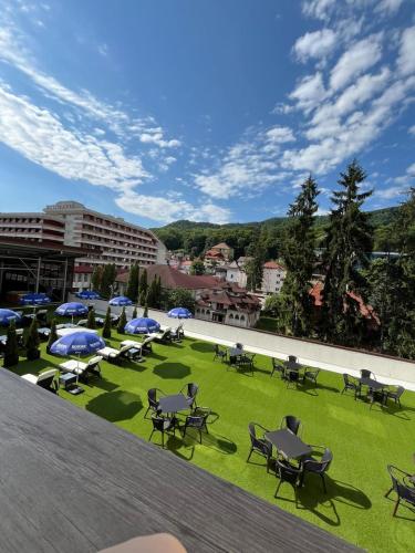 a group of tables and chairs on a field of grass at Hotel Cascada BAILE OLANESTI in Băile Olăneşti