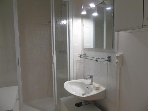 une salle de bain blanche avec un lavabo et une douche dans l'établissement Les Mesanges Bleues, à Saint-Jean-de-Monts