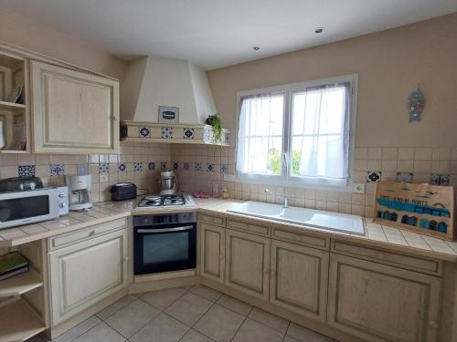 une cuisine avec une cuisinière, un évier et un micro-ondes dans l'établissement Pré-Rochet, à Saint-Jean-de-Monts