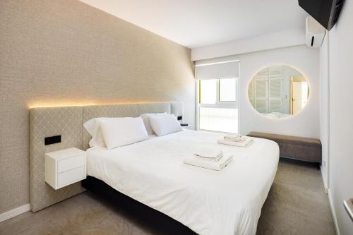 a bedroom with a large white bed with a mirror at Quinta Do Romão in Vilamoura