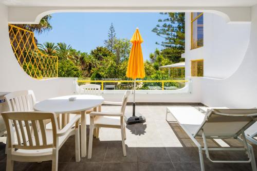 a patio with a white table and chairs and an umbrella at Quinta Do Romão in Vilamoura
