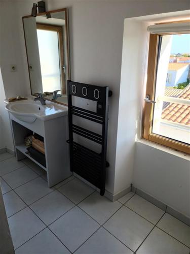 une salle de bain avec un lavabo et un miroir dans l'établissement Maison avec vue sur le port, à Port-Joinville