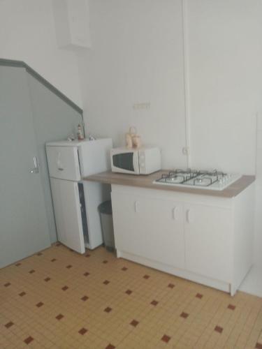 une cuisine avec des placards blancs et un four micro-ondes sur un comptoir dans l'établissement La plaisance tilleul, à Notre-Dame-de-Monts