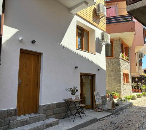 a white building with a wooden door and a table at Casa Mint in Sozopol